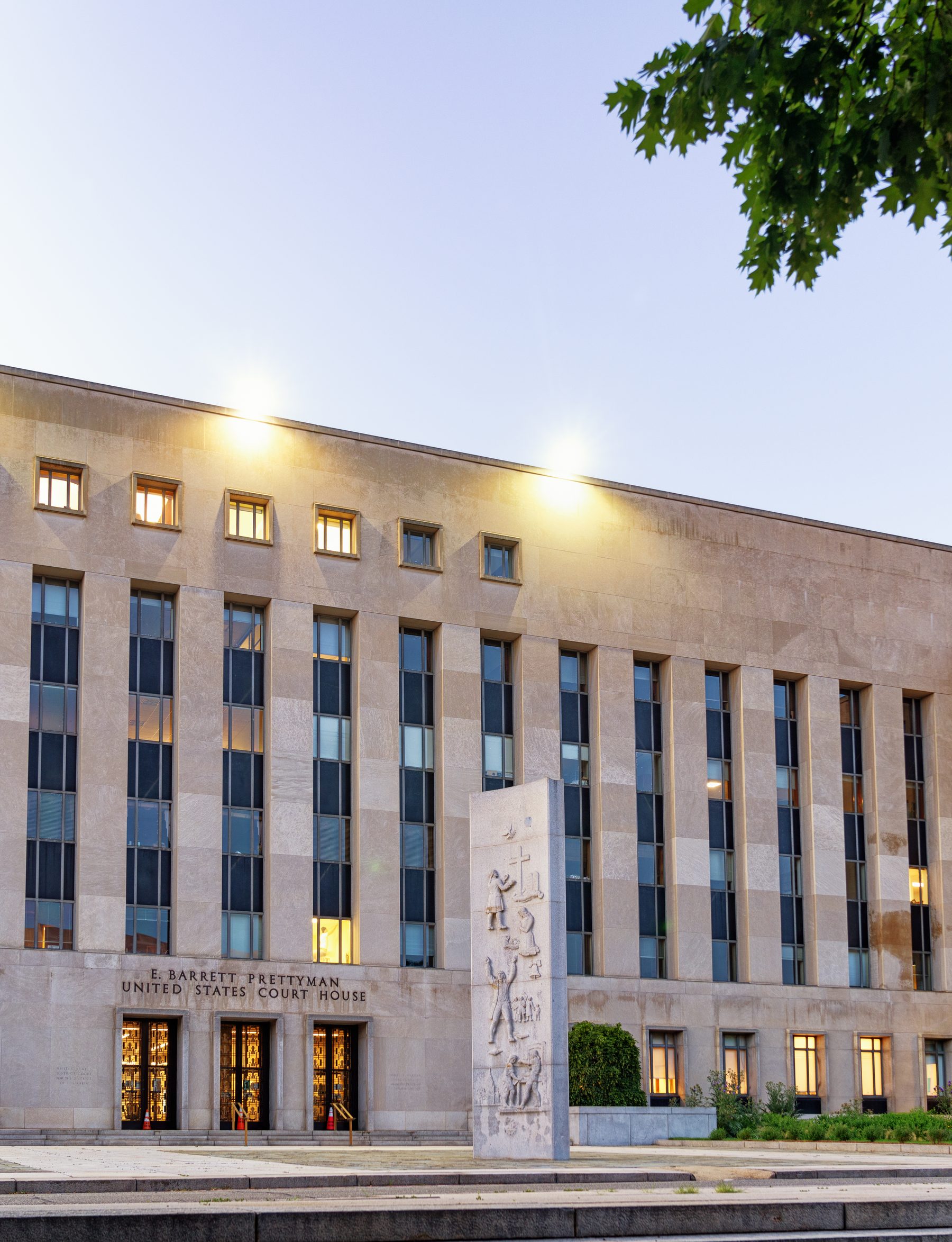 Fachada de pedra clara do tribunal E. Barrett Prettyman, em Washington, com colunas, bandeiras dos Estados Unidos e o nome do prédio acima da entrada