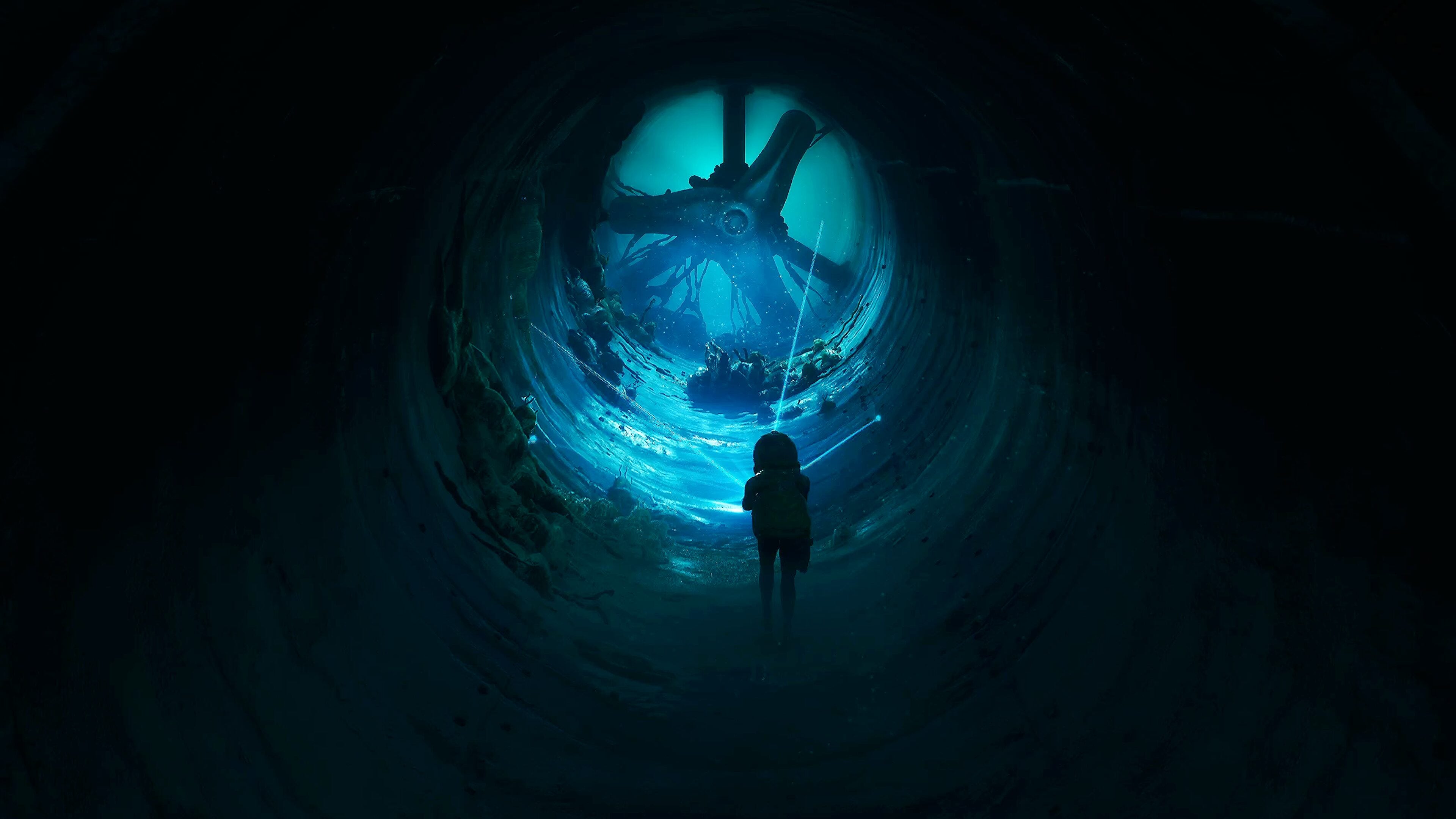 Silhueta de Cel em pé de costas em túnel escuro e circular, de jaqueta e calça comprida, olhando para frente iluminada por feixes de luz azul em direção a uma enorme estrutura mecânica de três pás no fundo