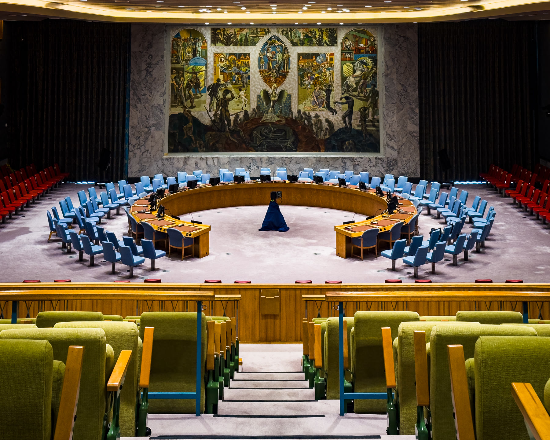 Câmara vazia do Conselho de Segurança da ONU em Nova York, com a mesa em ferradura e o emblema das Nações Unidas ao fundo