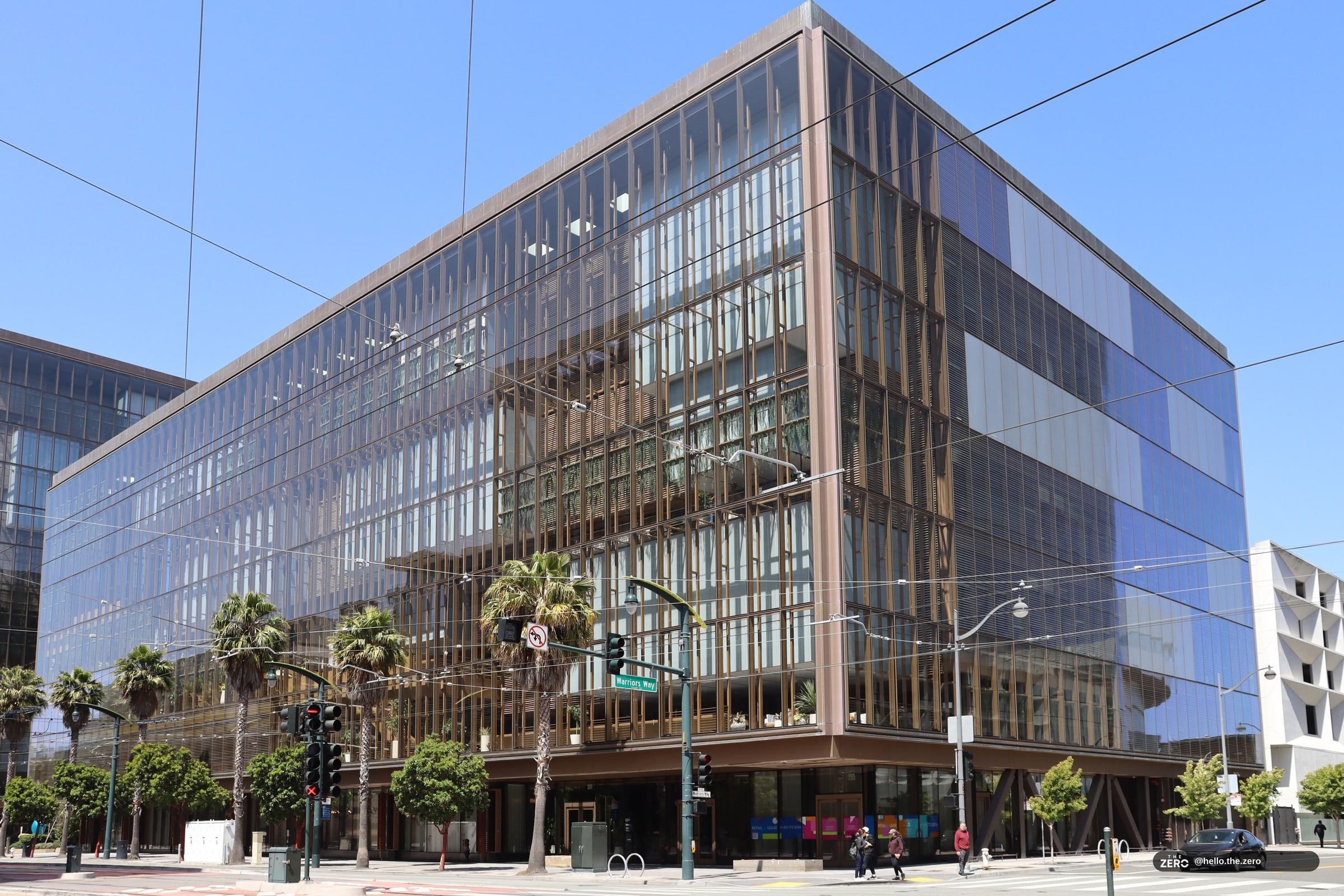 Prédio de vidro espelhado de vários andares no 1515 Third Street, em Mission Bay, São Francisco, com céu azul e palmeiras na calçada